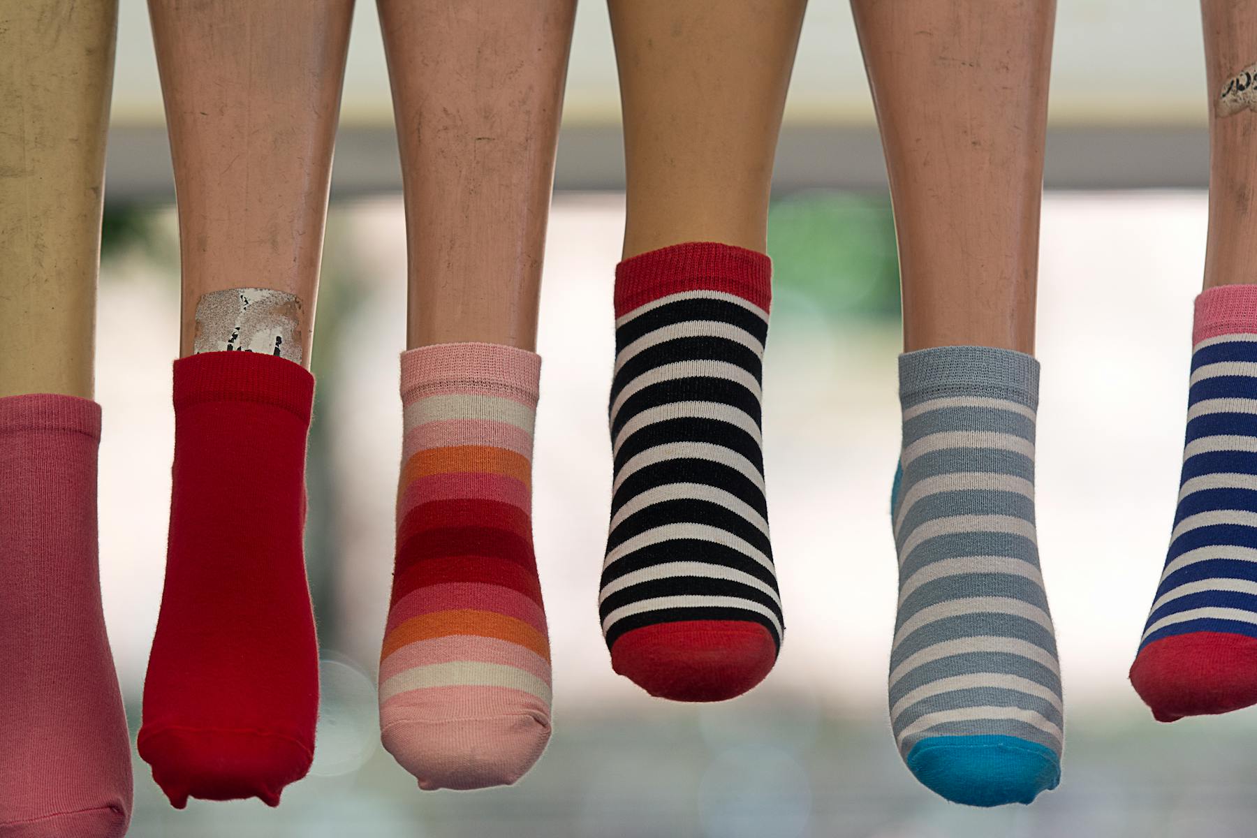 A vibrant array of striped socks displayed on mannequin legs, showcasing fashion variety.